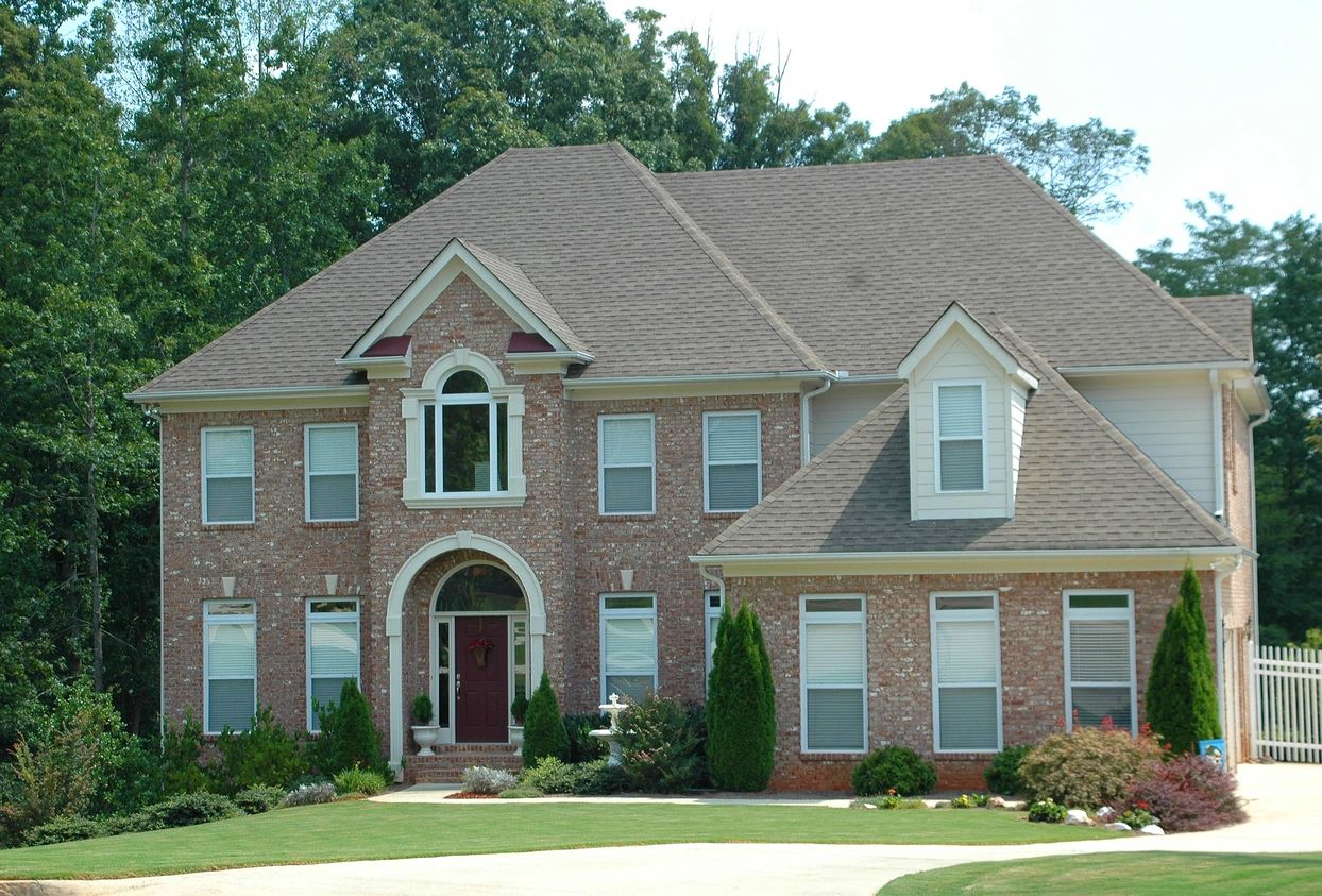 A large brick house with a red door and windows.