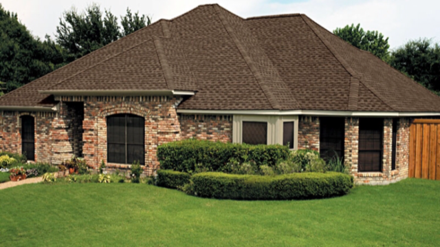 A large brick house with green grass in front of it.